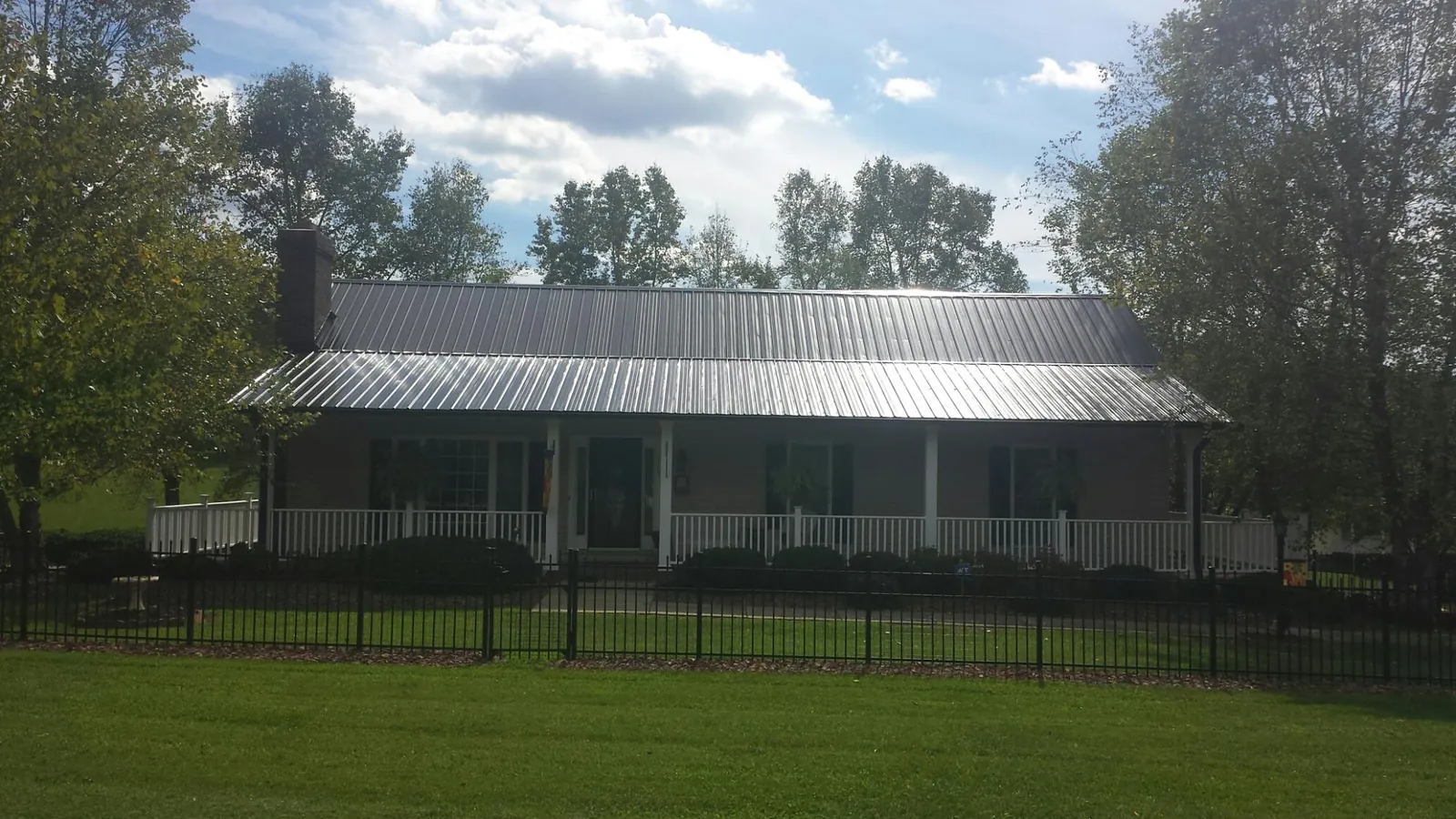 Gray metal roof on a brick ranch with a full width front porch — Gutter Guard Installation work by our crew in Apple Valley