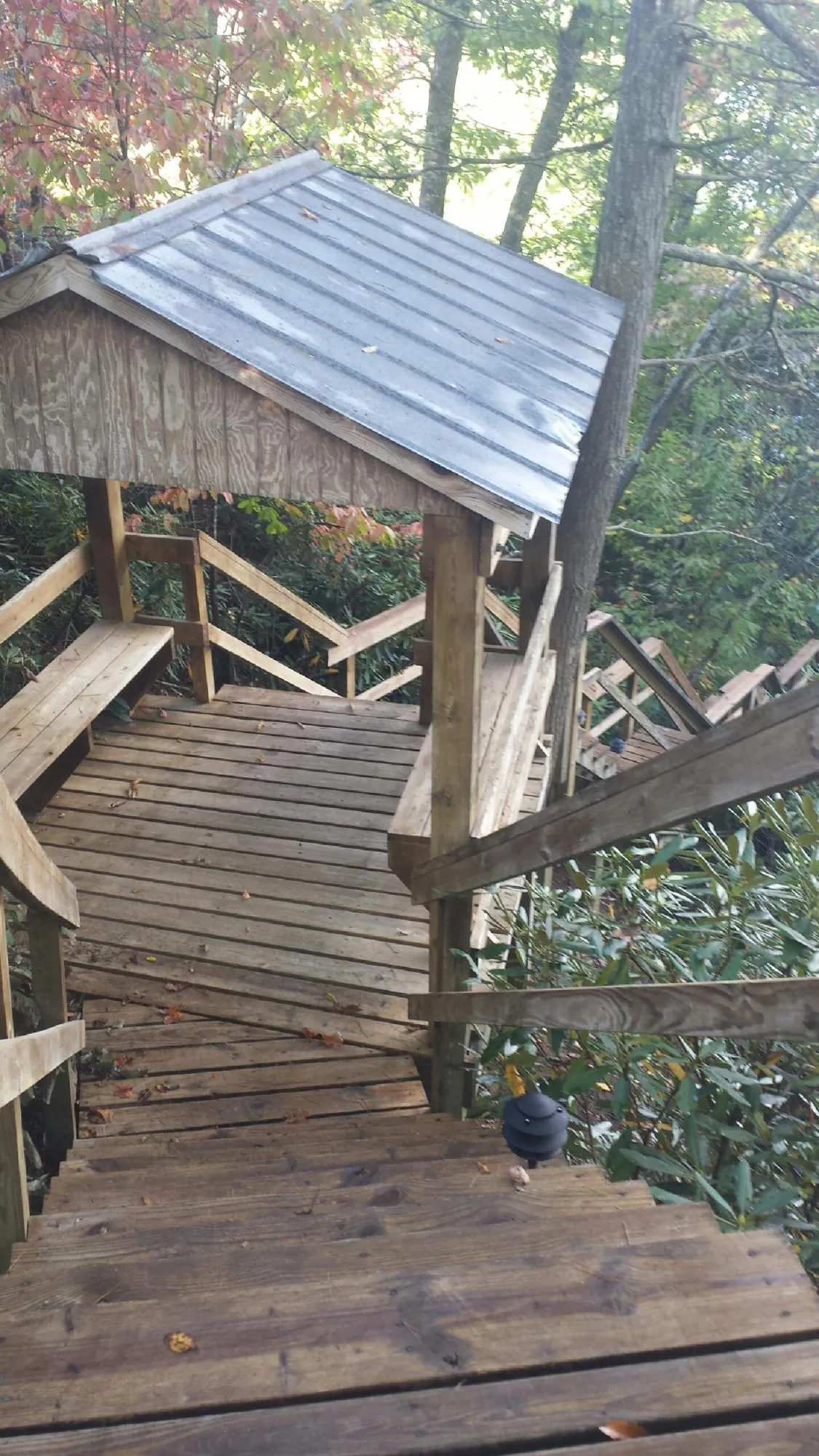 Metal roofed shelter over wooden steps on a wooded walkway — Skylight Repair & Installation work by our crew in Apple Valley