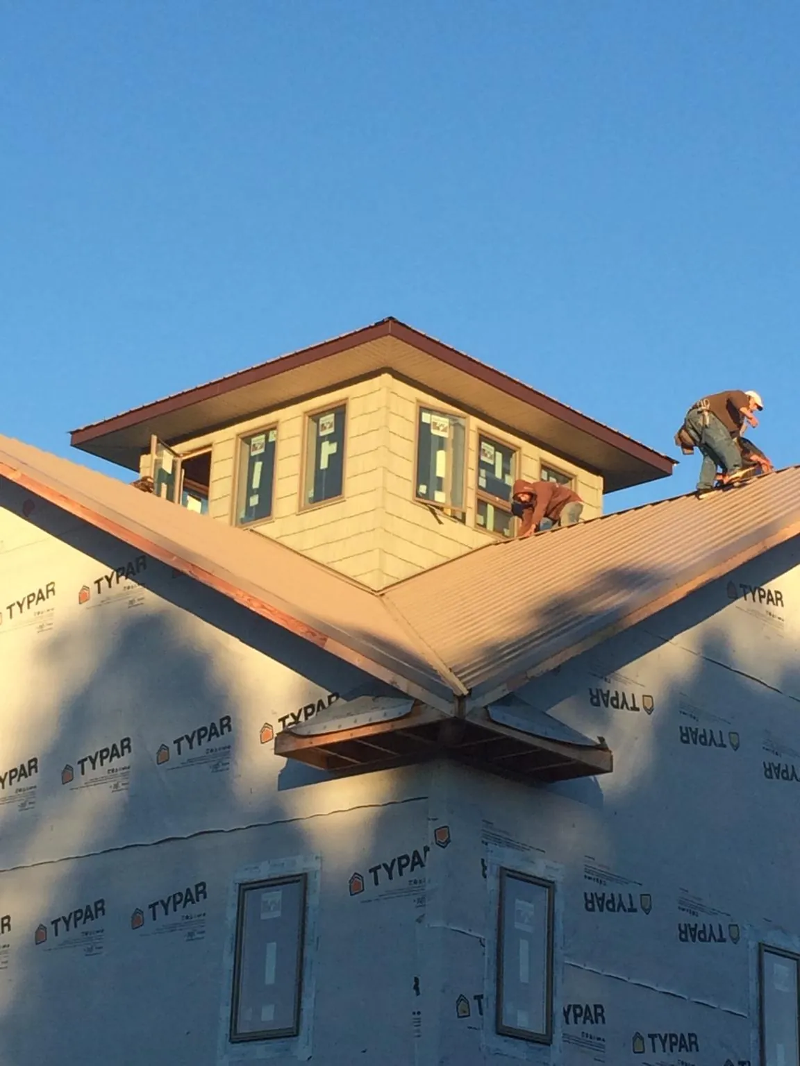 Roofers working around a rooftop cupola on a new metal roof at sunset — Roof Waterproofing in Apple Valley by Roofing Brothers